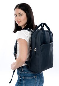 Donkerblauwe leren rugzak met dubbele bovenhandvatten, verstelbare riemen en voorvak met rits. Strak ontwerp met een gladde textuur en minimale hardware.