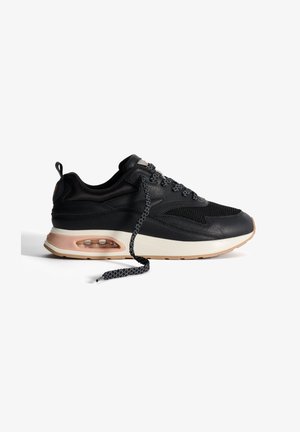 Sneaker nera con parte superiore in rete, dettagli in pelle testurizzata, un cuscinetto d'aria trasparente nella suola e lacci neri a motivo.