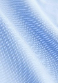 Tissu synthétique bleu clair avec une texture lisse, présentant un motif à pois subtil et des dégradés de couleur pour une profondeur.