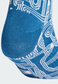 Kék zokni fehér geometriai mintával, puha, texturált anyagból készült. A mintában vonalak és ívek találhatók, kiemelve a kényelmet és a jó illeszkedést.