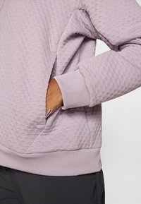 Kerge lavendlilise tooni struktureeritud sweatshirt, millel on mugav lõige, tasku ja soonilised varrukad. Kangas on peene, üles tõstetud mustriga.