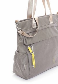 Sac tote gris texturé avec poignées beige, poche latérale, fermoir en métal et cordon jaune attaché à un mousqueton argenté.