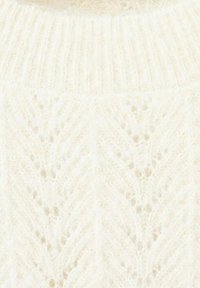 Pull en tricot couleur crème avec un motif en chevrons texturé, une texture douce et duveteuse, et un col côtelé.
