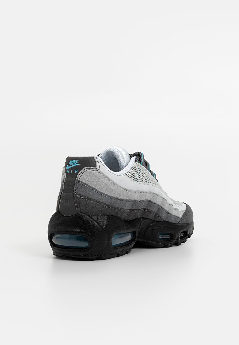 Las zapatillas Nike Air Max 95 en negro y gris cuentan con una parte superior de malla, suela acolchada y acentos azules. La vista de perfil destaca su diseño en capas.