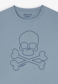 Lichtblauwe katoenen t-shirt met een grote marineblauwe afbeelding van een schedel en gekruiste botten, met "Scalpers Co." gedrukt nabij het ontwerp.