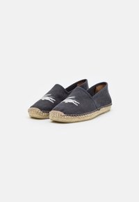 Espadrilles avec dessus en toile gris foncé, semelle enveloppée de jute et détail de logo brodé blanc à l'avant. Design à enfiler.