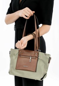 Borsa verde e marrone con tasca anteriore con zip, dettagli in pelle, doppi manici rotondi e elementi decorativi in metallo.
