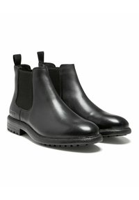 Bottines Chelsea en cuir noir avec panneaux élastiques sur les côtés, languettes de traction et semelles en caoutchouc texturé pour une meilleure adhérence. Fini lisse avec un détail de logo subtil.