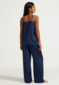 Navy satin pajama set featuring a sleeveless top with lace accents and wide-leg pants, all in a smooth, lightweight fabric.