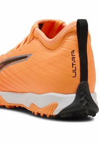 Scarpa sportiva arancione brillante con tomaia sintetica strutturata, dettagli neri e suola bianca. Presenta una scritta "ULTRA" ben visibile sul tallone.