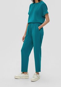 Teal sweatshirt en bijpassende joggers van zacht materiaal, met een relaxte fit, opgerolde mouwen, zijzakken en een elastische tailleband.
