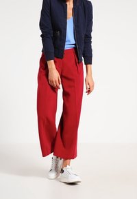 Červené široké kalhoty, námořnická bomber bunda, světle modré tričko a bílé tenisky. Hladký materiál, zkrácený design bundy a uvolněný střih.