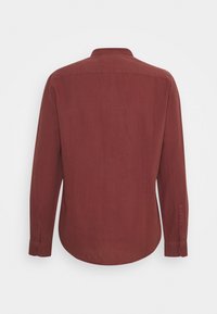 Chemise homme manches longues couleur rouille avec poignets boutonnés, vue de dos sur fond blanc uni.