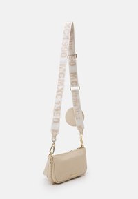 Béžová kožená crossbody taška se zlatým kováním, obsahující tkaný popruh s opakujícím se vzorem loga a kulatým texturovaným detailem na boku.