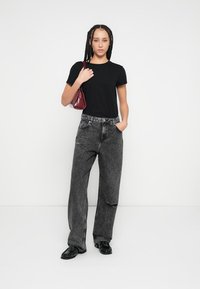 Fekete póló, magas derekú szürke farmernadrág kopott részletekkel, kiegészítve egy kis bordó kézitáskával és fekete cipővel.