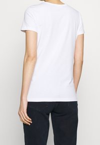 White cotton t-shirt with short sleeves, a crew neck, and a fitted shape. The fabric appears smooth with a slight stretch.