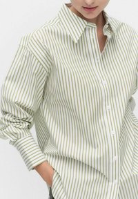 White button-up shirt with green vertical stripes, featuring a collar and long sleeves. Fabric has a smooth texture. Casual fit style.
