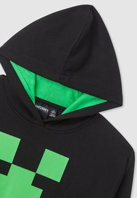 Felpa nera con interno verde e design di un volto verde pixelato sulla parte anteriore. Realizzata in tessuto morbido con cappuccio regolabile.