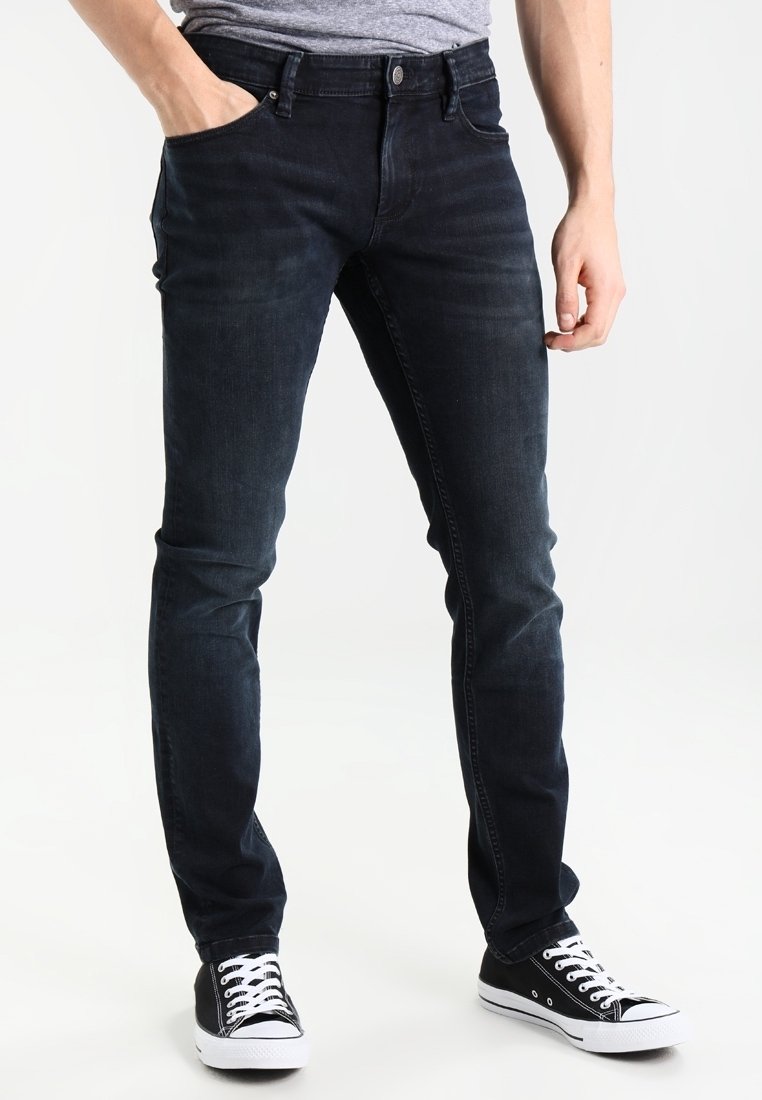 Mörka denimjeans med slim fit, som har framfickor, dragkedja och synlig sömnad. Kombinerat med svarta och vita sneakers.