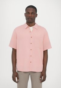 Short-sleeve button-up shirt in light pink fabric, featuring a chest pocket and brown buttons. Smooth texture with a relaxed fit.