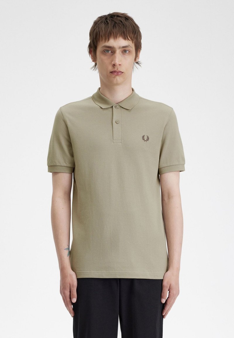 Polo de color verde oliva con mangas cortas, tapeta de tres botones y logotipo bordado en el lado izquierdo del pecho. Tejido de algodón suave, diseño minimalista.
