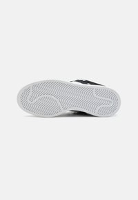 Semelle de chaussure avec un motif de gomme blanche présentant des lignes en zigzag et courbes, affichée sur un fond blanc uni.
