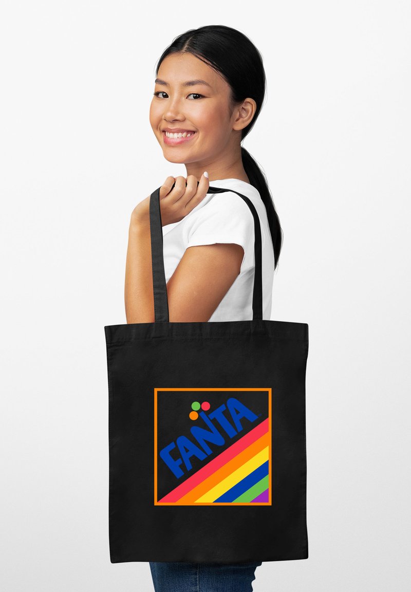 Borsa tote nera con manici lunghi, presenta un logo Fanta colorato su un vivace design a strisce arcobaleno all'interno di un bordo arancione.