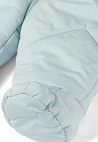 Close-up van lichtblauwe gewatteerde jas mouwen met gequilt stiksel en elastische manchetten op een witte achtergrond.