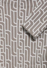 Sweter dzianinowy z geometrycznym wzorem splecionych kształtów w brązie i bieli. Miękka tekstura z wyraźnym ściągaczem i złożonym rękawem.