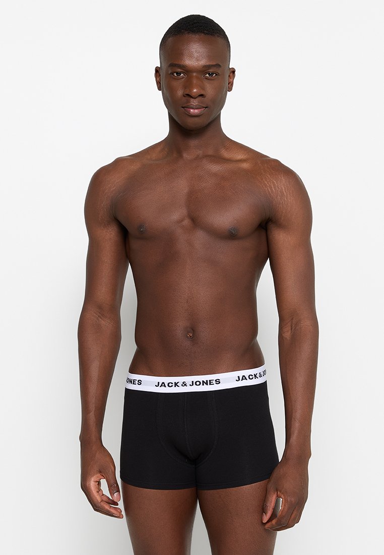 Schwarze Boxershorts mit einem weißen Elastikbund, der das Logo "JACK & JONES" trägt. Das Modell steht in neutraler Pose und zeigt Passform und Design.