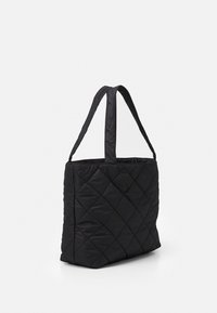 Sac en toile noir matelassé avec deux longues poignées, présentant un motif géométrique en losanges et une texture douce et rembourrée.