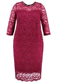 Burgundyröd spetsklänning med blommönster, trekvartslånga ärmar och vågig nederkant. Har rund halsringning och figurnära silhuett.