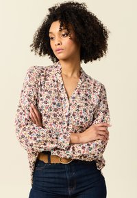 Blumenbluse aus leichtem Stoff, mit beigem Hintergrund und mehrfarbigen Mustern, subtiler Rüschenkragen und Knopfleiste.