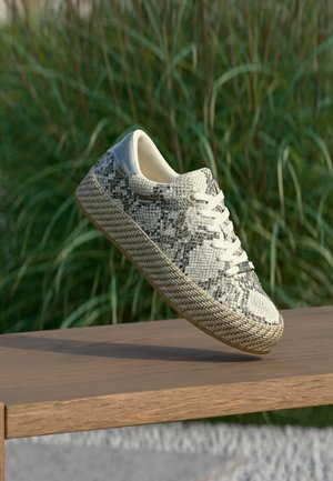 Sneakers med et struktureret snakeprint-design i cremefarve og en naturlig vævet sål. Hvide snørebånd og en let, afrundet form.