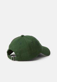 Mørkegrønn baseballcaps sett fra baksiden, med justerbar reim og flat skjerm. Bakgrunnen er ensfarget hvit.