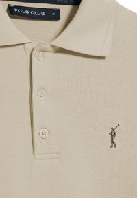 Polo shirt beige realizzato in tessuto testurizzato, con una patta a tre bottoni e una piccola figura ricamata sul lato sinistro del petto.