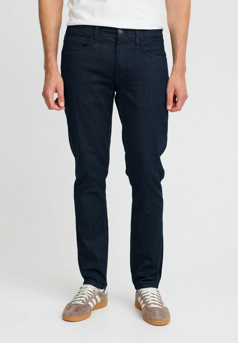 Mörk denimjeans med slim fit, standard femficksdesign och knäppning. Bärs med ljusa sneakers.