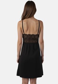 Zwarte jurk met dunne bandjes, voorzien van een kant bodice en een zachte, vloeiende rok. De kant heeft bloemenpatronen en geschulpte randen.