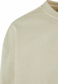 Világos bézs, bordás pulóver, kerek nyakkal, puha tapintással és lelapult vállvarrással.