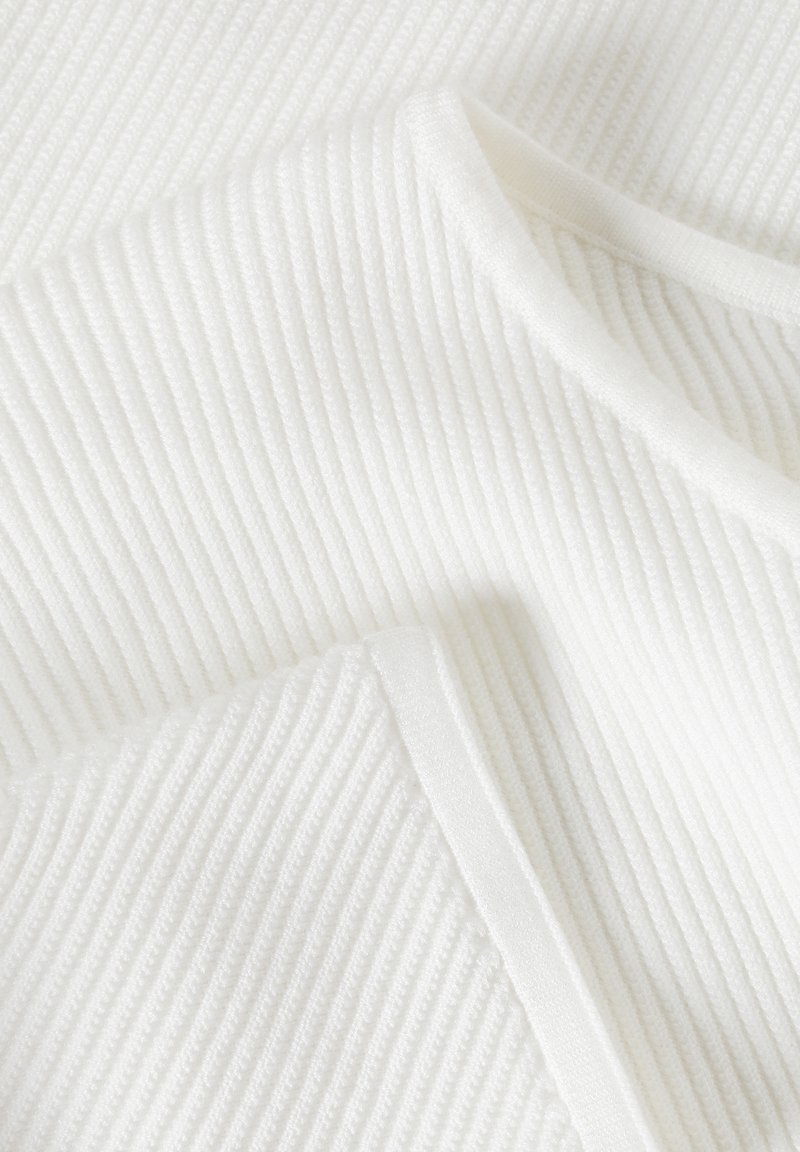 Biała, żebrowana tkanina z teksturowanym wzorem, z gładkimi krawędziami i delikatnym połyskiem, złożona w taki sposób, aby pokazać głębię i strukturę.