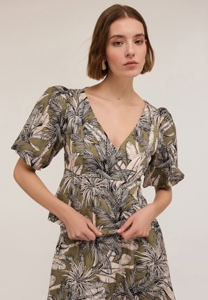 Top floreale verde oliva con maniche corte a sbuffo, scollatura a V profonda e vita arricciata. Il tessuto ha una texture liscia e un design botanico.