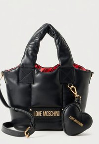 Musta nahkainen käsilaukku, jossa tikattu pinta, kaksi kahvaa, irrotettava olkahihna ja sydämenmuotoinen charm, jossa lukee "LOVE MOSCHINO" kullassa.