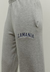 Szare dresowe spodnie wykonane z mieszanki bawełny, z bocznymi kieszeniami i granatowym haftem "LAMANIA" na lewej udzie.