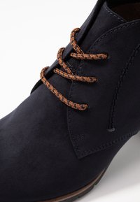 Navy siniväri nubuck syksyboot, jossa on pruunid lahnade sussünad, sileapind ja õmmeldud detailid ääre ääres.