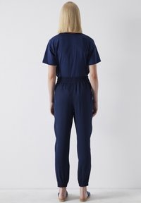 Navyblauwe jumpsuit van zachte stof, met een relaxte pasvorm, korte mouwen, elastische tailleband en taps toelopende broekspijpen met elastische boorden.