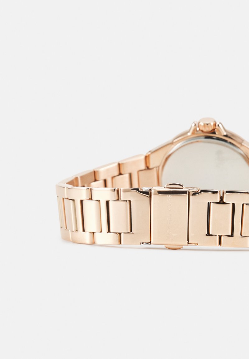 Roséguld metallklocka med en länkad armbanddesign. Har en rund urtavla, minimalistisk stil och en polerad finish.