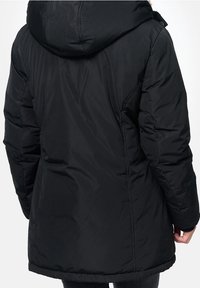 Svart pufferjacka med huva, med en slät yta, medellång längd och sidostygnsdetaljer. Ingen synlig hårdvara eller accenter.