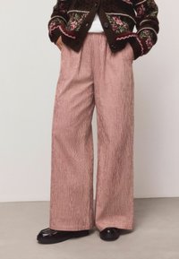 Pantaloni cu croială largă, în model carouri roșii și albe, confecționați dintr-un material ușor cu textură fină și design cu pliuri în față.