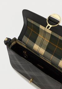 Fekete bőrtáska steppelt külsővel, arany hardware-rel és zöld és bézs árnyalatú kockás bélésével. Cipzáras zsebbel rendelkezik.