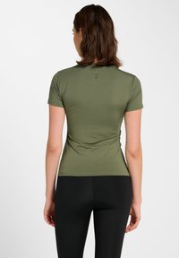 Eng anliegendes, olivgrünes Kurzarmoberteil mit glatter Textur, das eine dezente Logodetail auf der Rückseite und einen Rundhalsausschnitt aufweist.